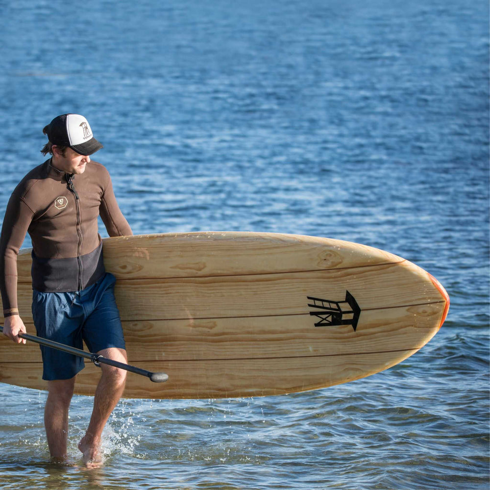 Man carrying a Tower wooden paddle board