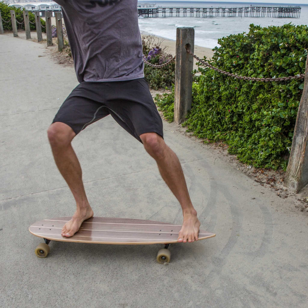 Man doing a power slide on a Tower boardwalk cruiser skateboard