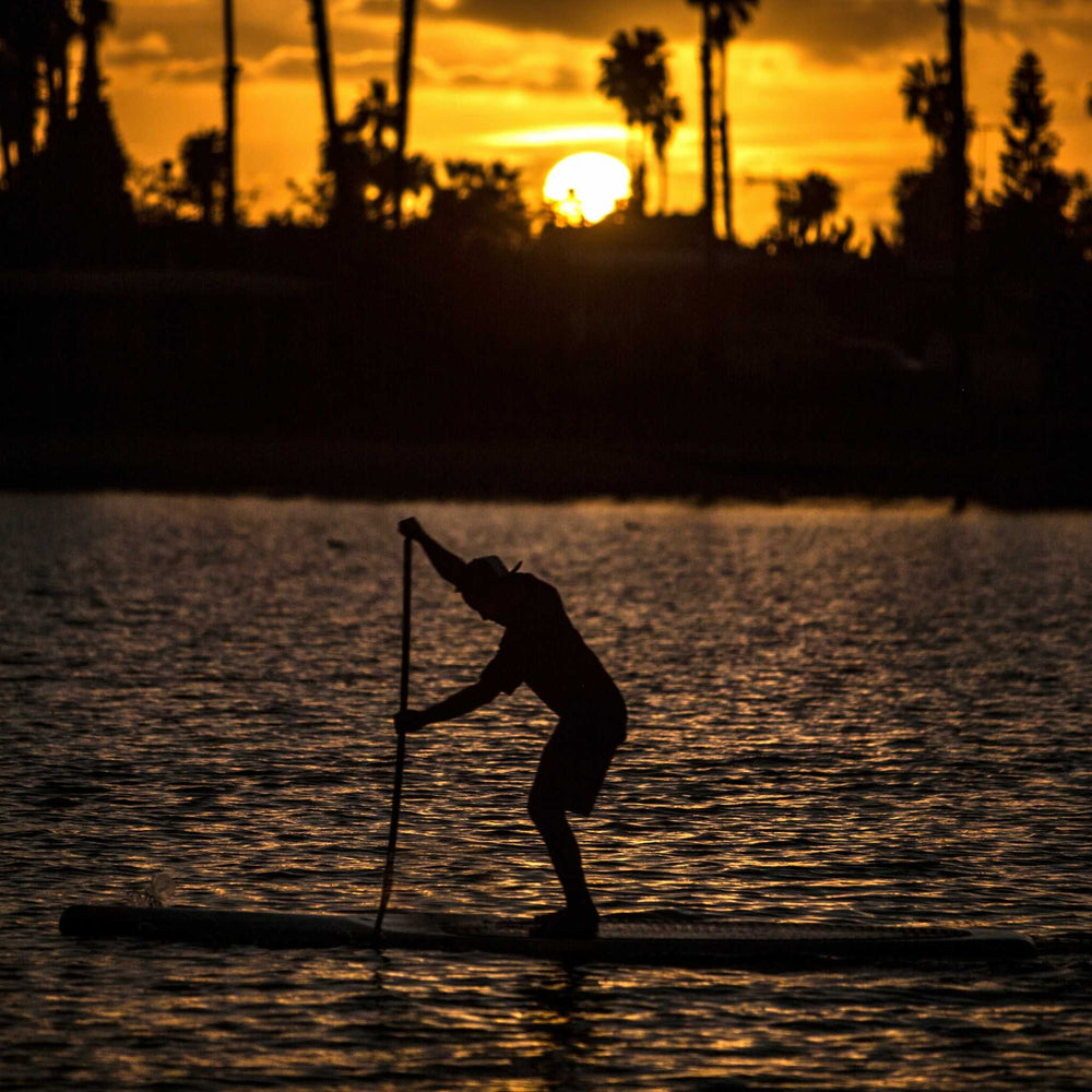 person paddle boarding in the sunset