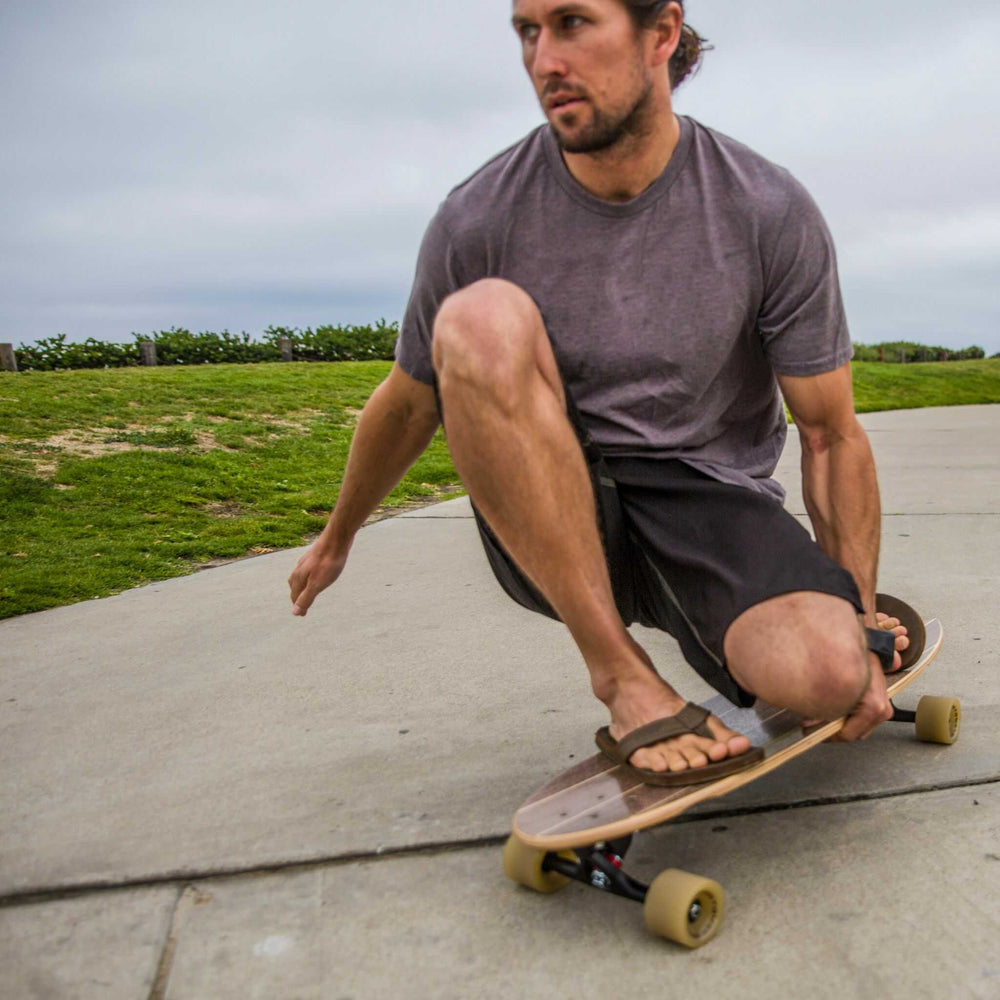 Man crouching while riding on a Tower boardwalk cruiser skateboard