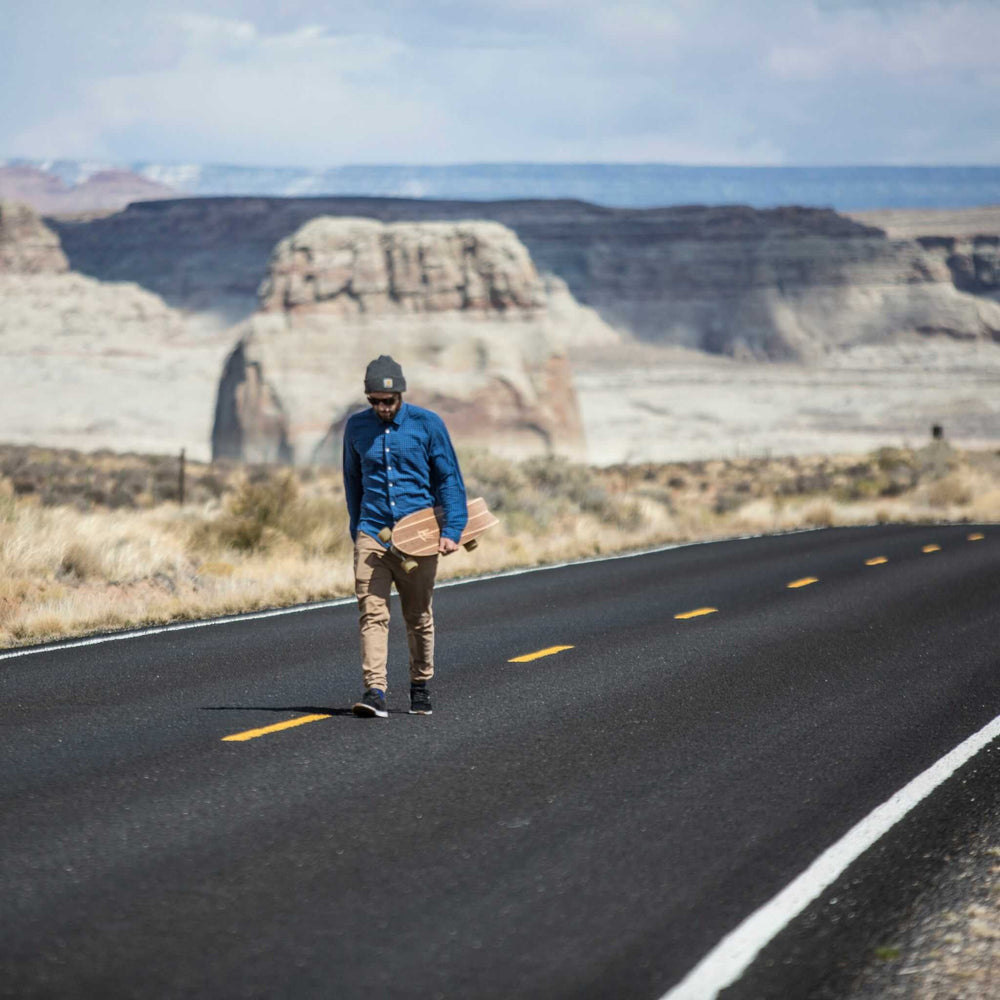 Man walking with Tower mini cruiser skateboard down an empty road