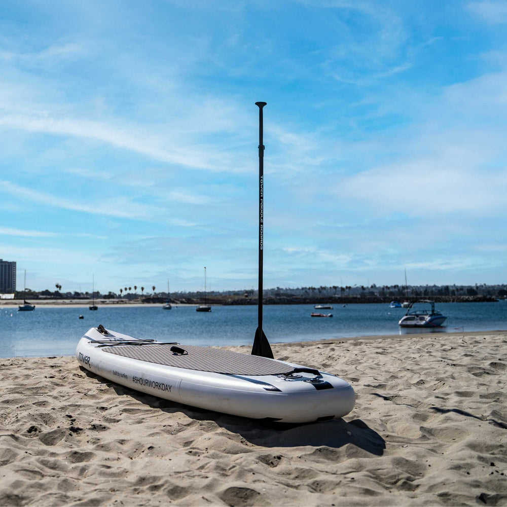 Tower paddle board with paddle stuck in the sand