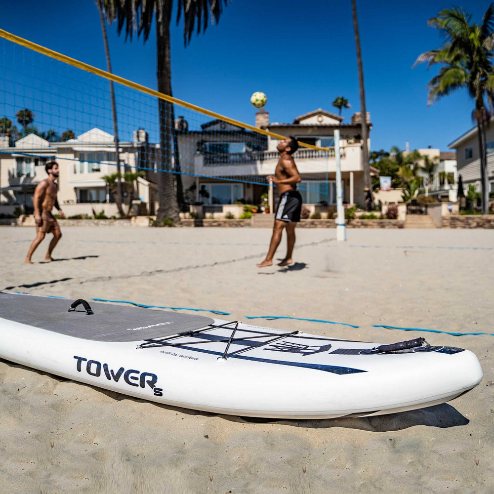 Tower paddle board with people playing volleyball in the background
