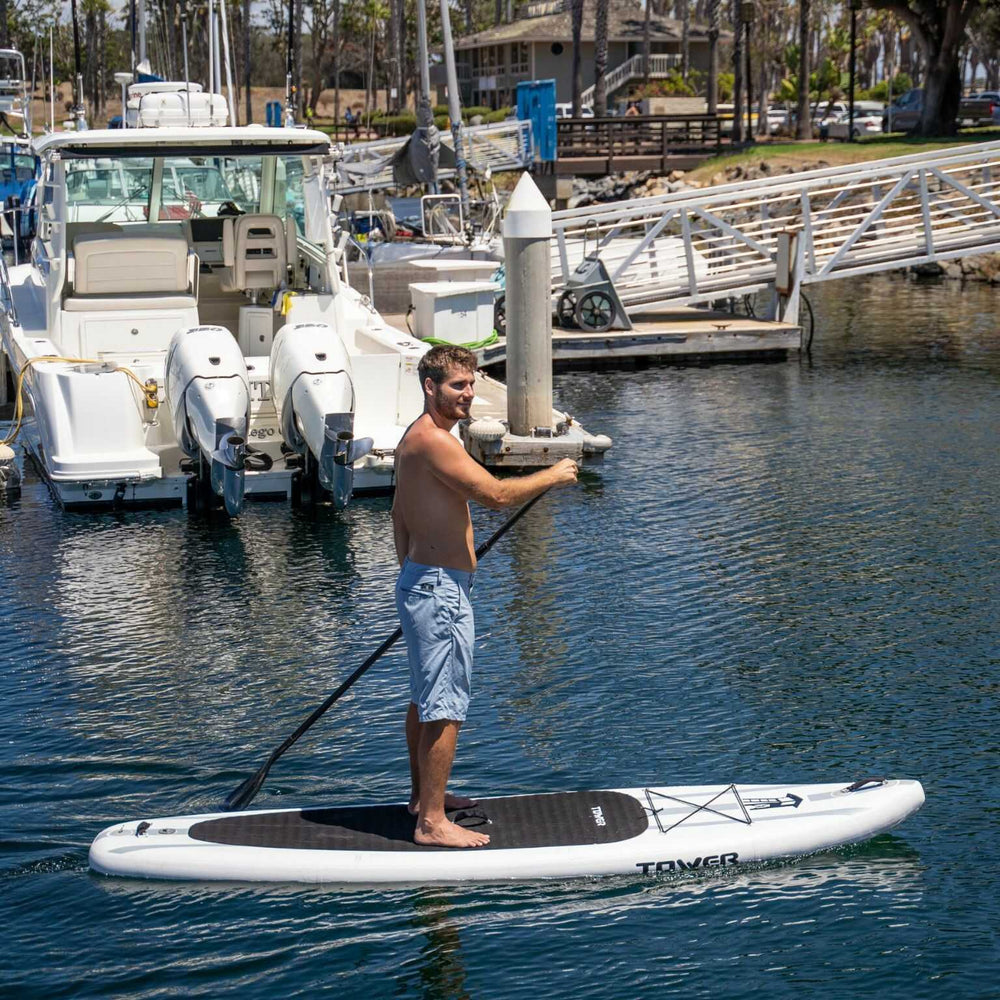 Man paddling a Tower paddle board through a boat marina