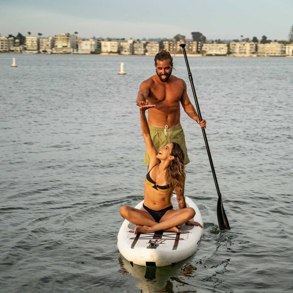Man and woman high fiving while riding on a Tower paddle board together. 