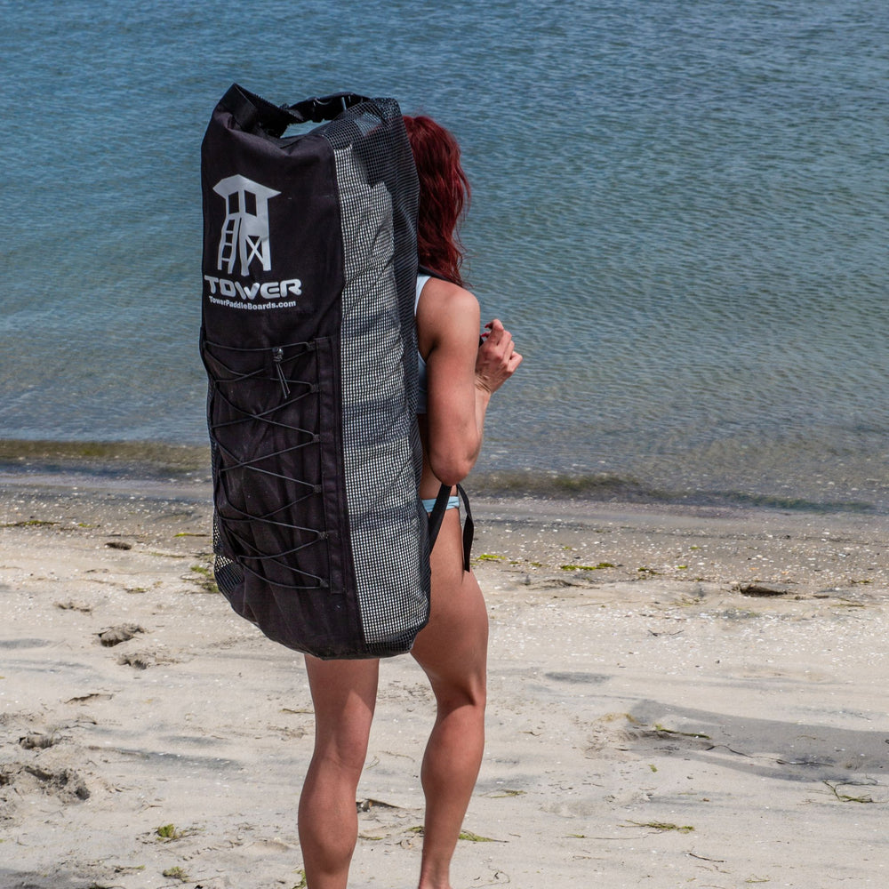 Woman wearing an iSUP backpack from Tower while on the beach