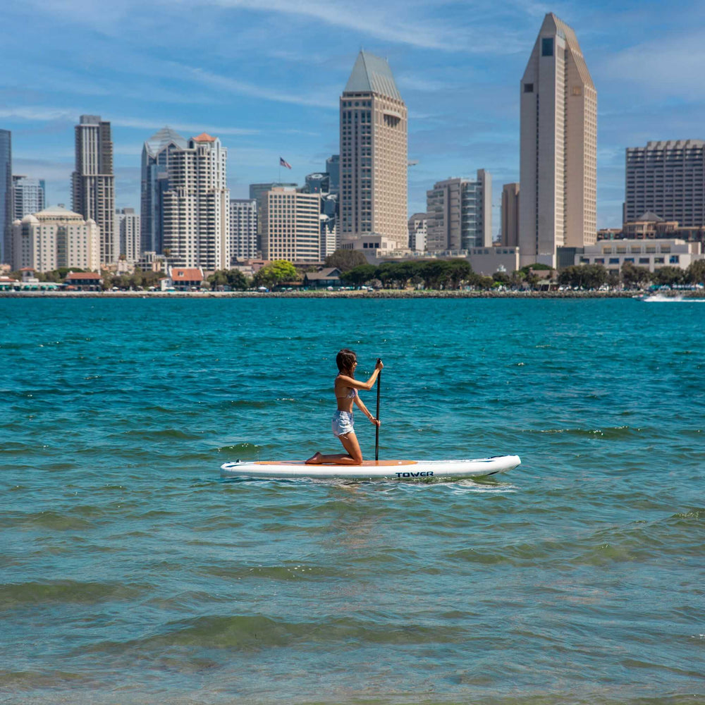 Girl paddle boarding in front of San Diego skyline