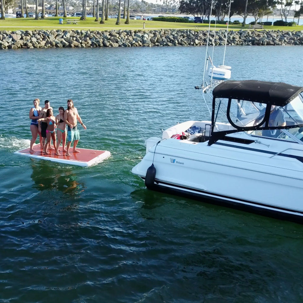 Group of people standing on a Tower swim step while being dragged behind a boat