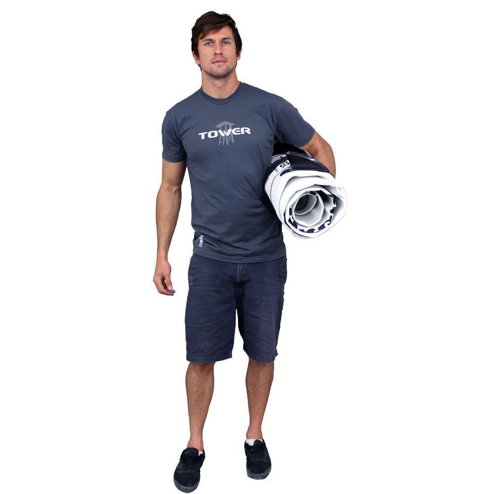 Man standing with paddle board under his arm while wearing a Tower paddle boards shirt