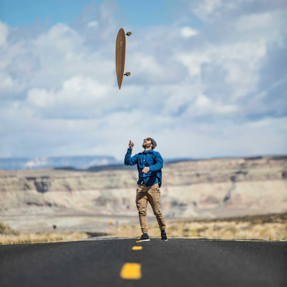 Man throwing a Tower boardwalk cruiser skateboard in the air